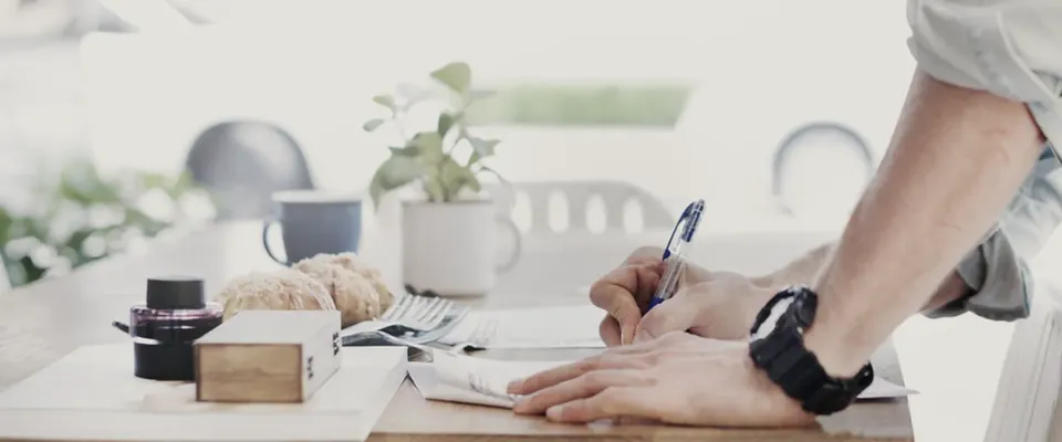 A kitchen table with paperwork and a pen, photographed from above with no people in frame