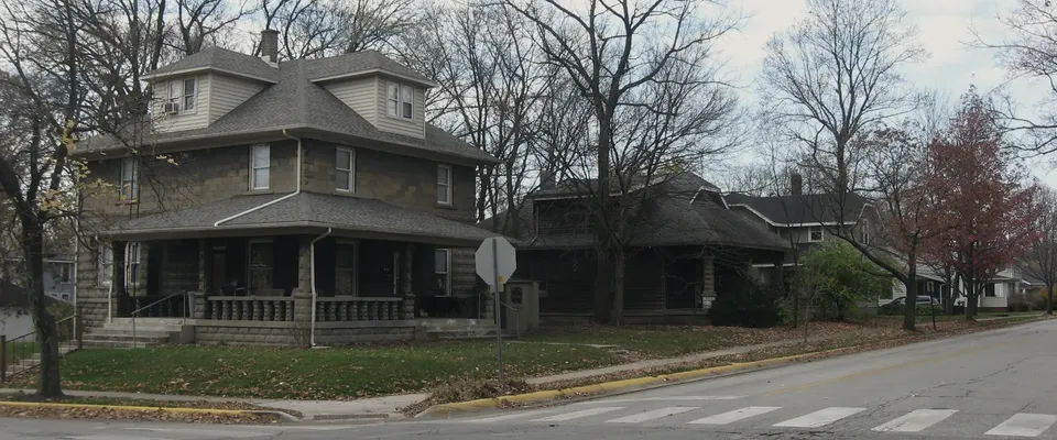 A row of modest single-family houses on a level residential street, photographed in soft daylight